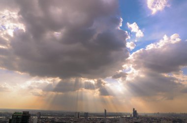 Güneş ışınları bulutların arasından geçiyor ve Bangkok şehrinin manzarası üzerinden gökyüzünde parlıyor. Önümüzde bekleyen güne hazırlanmak için enerjik bir his yaratıyor. Boşluğu kopyala, Seçici odak.