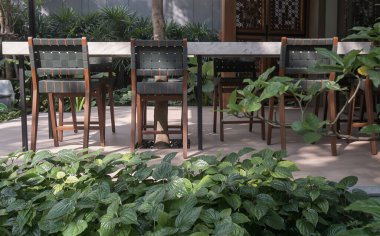 Evin arka planında beyaz mermer masa olan ahşap yeşil sandalyeler. Yemek masası bahçede hazır. Seçici odak.