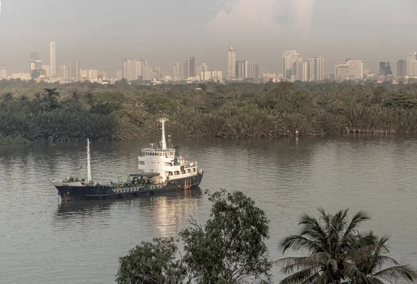バンコク 2020年11月20日 チャオプラヤ川の夕方に高層ビルが建ち並ぶ緑の森の前に停泊する貨物船 選択的焦点 — ストック写真