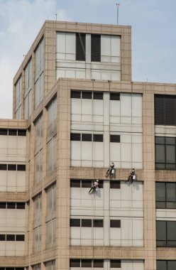 Bangkok, Tayland - 29 Aralık 2020: Yüksek katlı ofis binasının camlarını temizleyen bir grup işçi. Seçici odak.