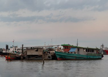 Bangkok, Tayland - 04 Ocak 2021: Chao Phraya nehrindeki küçük iskelenin önüne park edilmiş küçük bir kargo gemisi. Seçici odak.