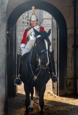 Londra, İngiltere - 19 Nisan 2019: Kraliçe 'nin can kurtaranlarından biri Kraliyet Sarayı' nda siyah bir atın üzerinde oturuyor. Seçici odak.