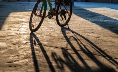 Sarı güneş ışınları park yerindeki bisiklet tekerleklerinden geçer. Yakın çekim, Seçici odak.