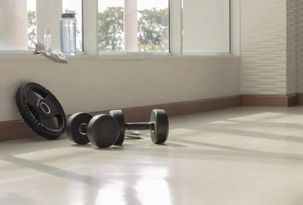 Spor salonunda ya da spor salonunda dambıllar, su şişesi ve alkol dezenfektanı var. Boş alanla spor egzersizleri yapmak için gerekli ekipman. Egzersiz konsepti, Seçici odak.