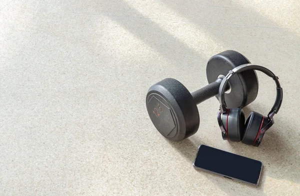 Egzersiz yaparken müzik dinlemek için Smartphone, Kulaklıklar ve Dumbbell kompozisyonu. Boşluğu kopyala, Seçici odak.