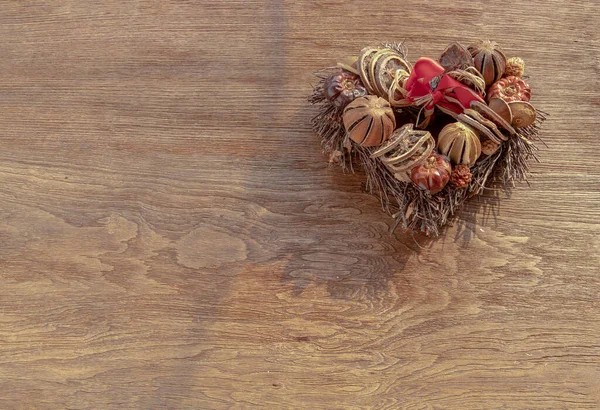 Different dry fruits over on twigs pile shape of heart on wooden background. Copy space, Selective focus.