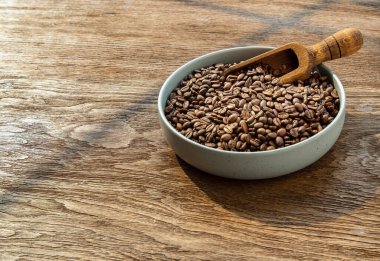 Seramik tabakta eski ahşap kepçeli kahve çekirdekleri metin için kopyalanmış ahşap arka planda. Yaşamak için alternatif kahve, kahve tarzı, seçici odaklanma..