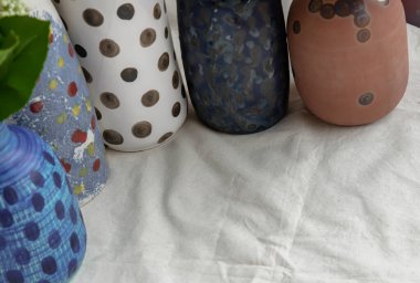 Beyaz desenli masa örtüsü üzerine çeşitli seramik benekli vazoların ayrıntıları. Ev dekorasyonu, metin için boşluk, Seçici odak.