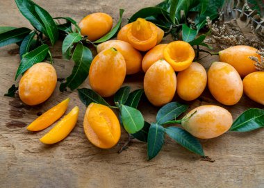 Taze Marian erikleri tatlı sarı veya ahşap arka planda yeşil yapraklı mayonez. Egzotik tropikal meyve kavramı, seçici odak.