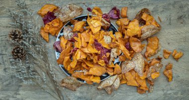 Dilimlenmiş tatlı patatesten yapılmış Tayland tatlıları seramik tabakta şeker (patates cipsi) ile kaplanmış kırsal ahşap arka planda kurumuş çiçekler. Seçici odak.