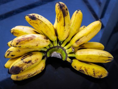 Bir demet Bayan Parmak Muzları. Siyah masada Tropikal Meyve Doğal Ürünleri. Seçici odak.