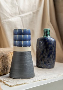 Beyaz desenli masa örtüsünde iki mavi el yapımı seramik vazo. Ev dekorasyonu, Boşluğu Kopyala, Seçici odak.