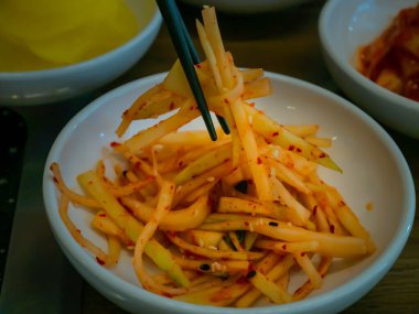 Yemek çubuğu kullanarak yemek için beyaz bir fincanda turp turşusu topladım. Asya mezesi turp turşusu, geleneksel Kore yemeği. Tam olarak odaklanamıyorum..