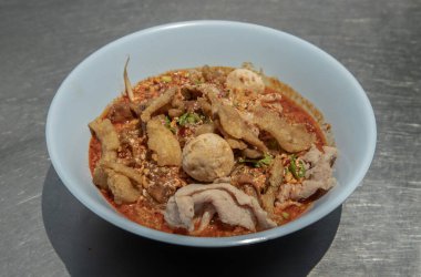 Tayland baharatlı erişte çorbası, haşlanmış domuz eti, domuz köftesi ve beyaz kasede yağlı domuz derisi. Tayland yemekleri, seçici odaklanma.