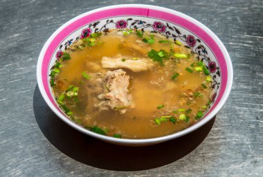 Soya sosu ve biberli taze domuz pirzolası çorbası. Beyaz kasede domuz kemiği çorbası, seçici odak.