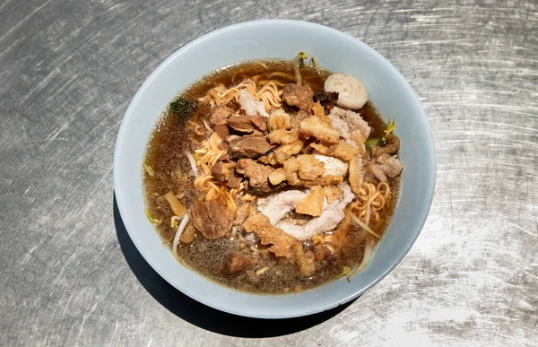 白鉢に豚肉のボールと脂ののった豚の皮を煮込んだ豚スープにインスタントラーメン タイ料理 トップビュー 選択的フォーカス — ストック写真