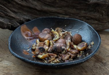 Kalan kestaneler eski ahşap arka planda siyah seramik tabakta. Tam olarak odaklanamıyorum..