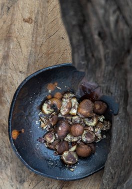 Kalan kestaneler eski ahşap arka planda siyah seramik tabakta. Seçici odak.