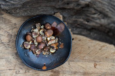 Kalan kestaneler eski ahşap arka planda siyah seramik tabakta. Seçici odak.