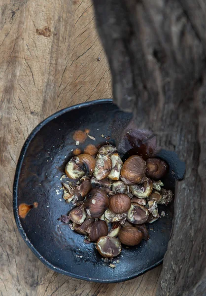 Kalan kestaneler eski ahşap arka planda siyah seramik tabakta. Seçici odak.
