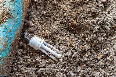 Yanmış enerji tasarruflu lamba kalıntıları kumsalda bırakılır. Tehlikeli ve zehirli elektronik atık. Seçici odak.