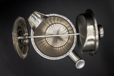 Cafetiere lavabosunun üst görüntüsü siyah arka planlı paslanmaz çelik sürahiye yerleştirilmiş. Fransız kahvesi. Cafetiere 'in soyut metal işi halterci gibi. Seçici odak.