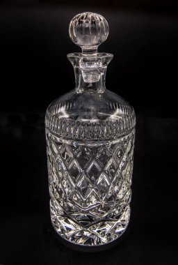 Kabartmalı boş kristal sürahi, siyah arka planda cam tıkaçla kapatılmış. Seçici odak.