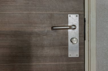 Ahşap kapı kolunda paslanmaz deliğinden yapılmış kapı kolu ya da kapı kolu ve anahtar deliği ayrıntıları. Metalik kapı kolu ve kilidi, seçmeli odak.