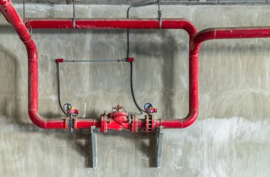 Beton duvarda basınç vanası olan kırmızı su ya da gaz boru hattı. Endüstriyel tüpler ve vanalar, boru endüstrisi ve yangın söndürme pompası, kopyalama alanı, seçici odak.