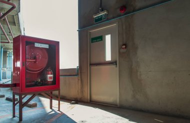 Yangın çıkışı kapısı ya da çıkış işareti olan yangın çıkışı kapısı ve park yerindeki kırmızı yangın söndürme ekipmanları dolabı. Önce güvenlik kavramı. Seçici odak.