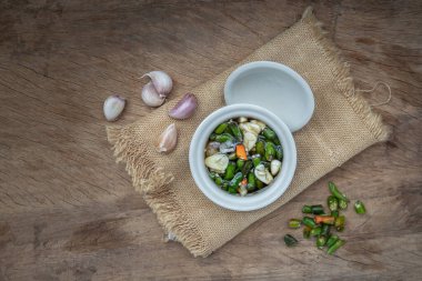 Tayland acılı balık sosu ve Tayland yeşili ve kırmızı biberli malzemeler, eski ahşap masada seramik beyaz bardakta sarımsak. Üst Görünüm, Boşluğu Kopyala, Odaklanma Seç.