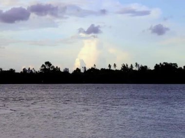 Güneş batmak üzereyken mavi ve bulutlu bir gökyüzü. Bulutların ve su kaynaklarının hızlı hareketi. Akşam Chao Phraya Nehri 'nde..