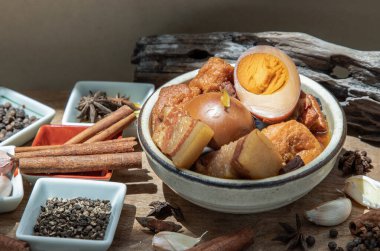 Haşlanmış yumurta (kai pa lo) ve Göbek Pork Çin beş baharatlı baharatlı soya peyniri anason yıldızı, tarçın, sarımsak ve karabiber ile süslenmiş kahverengi soslu eski ahşap masa, Asya yemeği, seçici odak noktası.