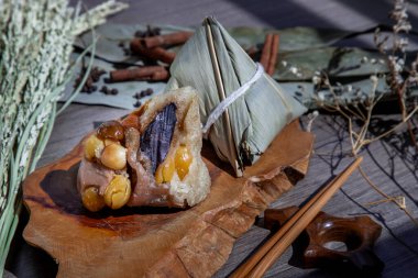 Çin pirinç köftesi (Zongzi) şekilli piramit şekilli, ahşap tabakta ve çubuklarda yaprak malzemeleriyle sarılı. Ejderha teknesinde (duan wu) ünlü Asyalı lezzetli el yapımı yemek festivali vesilesi.