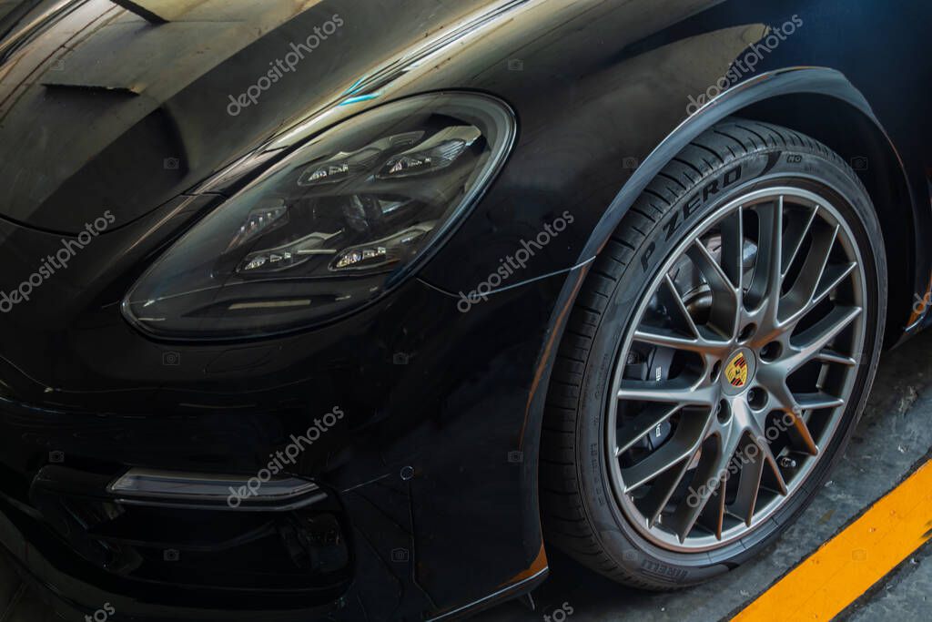 Bangkok, Thailand - 06 Jun 2021 : Close-up of Headlights, Wheel, and Rim of Black porsche sports car. Selective focus.