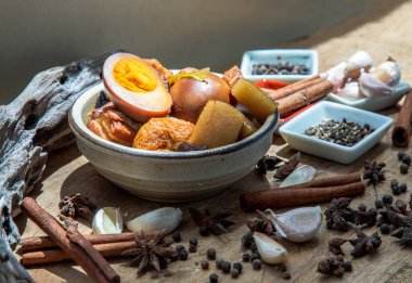 Haşlanmış yumurta (kai pa lo) ve Göbek Pork Çin beş baharatlı baharatlı soya peyniri anason yıldızı, tarçın, sarımsak ve karabiber ile süslenmiş kahverengi soslu eski ahşap masa, Asya yemeği, seçici odak noktası.