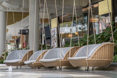 Bangkok, Tayland - 24 Mayıs 2021: Boş zamanlarında minderli bir iple dört hasır rattan sallanan sandalyeyi gevşetmek. Seçici odak.