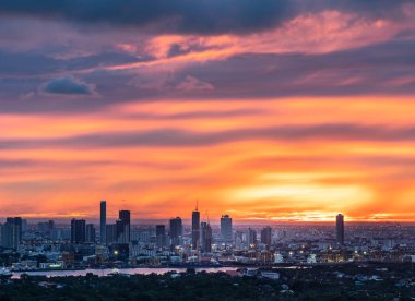 Bangkok 'un büyük metropoliten şehrinin üzerinde turuncu gökyüzünde bulutla güneşin doğuşunun muhteşem manzarası. Boşluğu kopyala, Seçici odak.