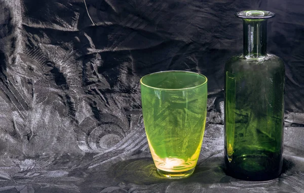彩色透明绿色玻璃杯和绿色玻璃瓶 用于饮水和在黑色背景上的表面反射 复制空间 选择性焦点 — 图库照片