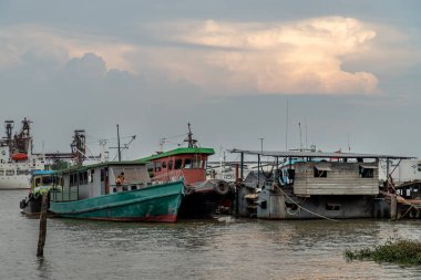 Bangkok, Tayland - 10 Nisan 2020: Küçük iskele yakınlarındaki Chao Phraya nehrinin ortasında kargo gemileri.
