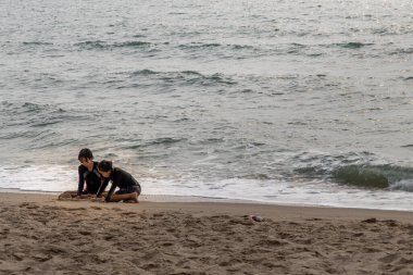 Phetchaburi, Tayland - 15 Mart 2020: Güneşli bir günde tropik plajda kum oynayan iki kız. Tatil gezisi. Seçici odak.
