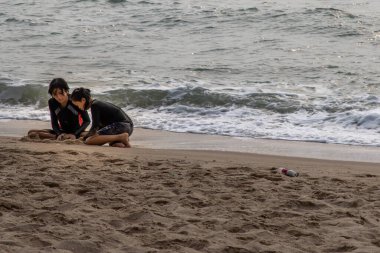Phetchaburi, Tayland - 15 Mart 2020: Güneşli bir günde tropik plajda kum oynayan iki kız. Tatil gezisi. Seçici odak.