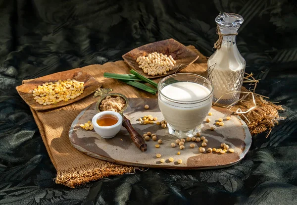 Soy products : A glass of Homemade soy milk and grains (soybeans) Served with brown sugar and honey on sackcloth with lighting in the morning. Alternative milk concept, Selective focus, Copy space.