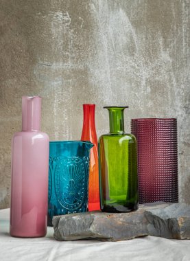 Pembe masa örtüsünde birçok farklı cam kavanoz ve yüzey yansımaları var. Farklı cam eşyalar grubu, seçici odak.