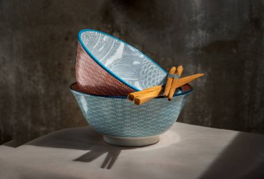 Pembe masa örtüsünün üzerinde tahta çubuklar olan iki seramik kasesi. Seramik tablo takımı, Güzel düzenleme, Kopyalama alanı, Seçici odak.