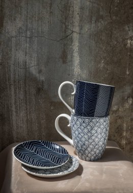 Pembe masa örtüsünde bardak altlığı olan iki seramik bardağı. Seramik tablo takımı, Güzel düzenleme, Kopyalama alanı, Seçici odak.