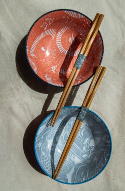 İki seramik kâsesi, üzerinde ahşap yemek çubukları olan kumaş kumaş kumaş. Seramik sofra takımı, Güzel düzenleme, Üst Görünüm, Seçici Odaklanma.