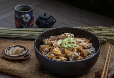 Japon domuz pirinci kasesi yumurta ve soğanlı (Donburi) turşulu zencefil ve ahşap masada yeşil çay ile servis edilir. Japon yemek tarzı..