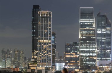 Gece Bangkok 'un aydınlık binaları ve gökdelenleri, gökdelenler gökdelenler, gökyüzü merkezi merkezde yer alan, gökyüzü merkezi ve ön planda Lumphini Park ağaçları olan bir park alanı.
