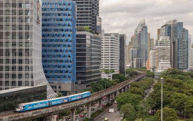 Önemli bir gökdelen binası, yüksek raylı bir BTS Skytrain ve aşağıda araç trafiği olan yollar, hepsi Bangkok gibi hareketli bir şehir merkezinin karakteristik özellikleri. Modern bir şehir manzarası. Duvar kağıdı, Poster ve Kopyalama alanı olarak kullan, Seçici odak.